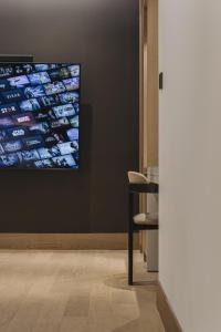TV colgada en una pared en una habitación con silla en Arban Hotel en Busan