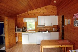a kitchen with white cabinets and a wooden wall at Skysstasjonen Cottages in Røldal