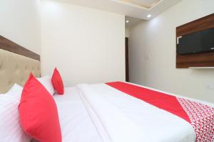 a bedroom with a bed with red pillows and a tv at OYO Hotel Dezzire in Ballabgarh