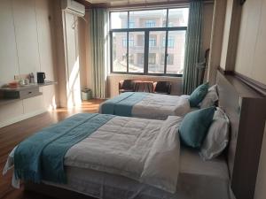 two beds in a room with a large window at Meizhou Cloudy B&B in Putian