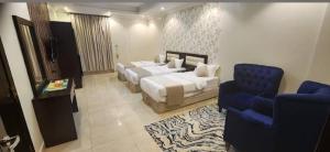a hotel room with two beds and a blue chair at الجوهرة البيضاء للشقق المخدومة in Jeddah