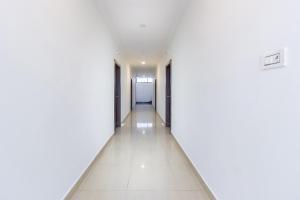 an empty hallway with white walls and white tile floors at Hotel Alpine Glow Heights in Trimulgherry