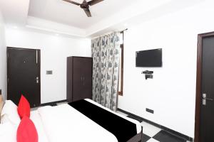 a bedroom with a bed and a flat screen tv at Capital O Peaceful Stays Near ISKCON Temple Noida in Noida