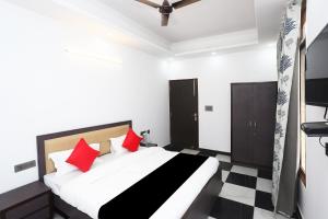 a bedroom with a bed with red pillows at Capital O Peaceful Stays Near ISKCON Temple Noida in Noida