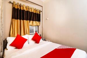 Un dormitorio con una cama con almohadas rojas y una ventana en OYO Kuber Residency Near Birla Mandir, en Calcuta