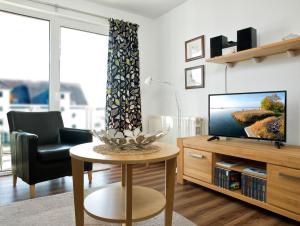 ein Wohnzimmer mit einem TV, einem Stuhl und einem Tisch in der Unterkunft Residenz am Yachthafen Hornhecht in Kirchdorf