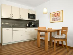 a kitchen with white cabinets and a wooden table and chair at Residenz am Yachthafen Hornhecht in Kirchdorf +22 photos