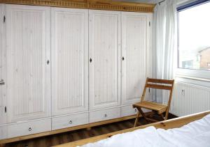 ein Schlafzimmer mit weißen Schränken, einem Stuhl und einem Bett in der Unterkunft Residenz am Yachthafen Hornhecht in Kirchdorf