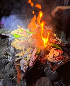 a bunch of food cooking on a grill with flames at Kerith Lodge in Port Vila