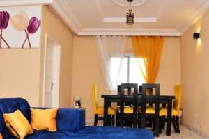 - un salon avec un canapé bleu et une table dans l'établissement Appartement meublé, 2 douches, 2 chambres, à Yaoundé
