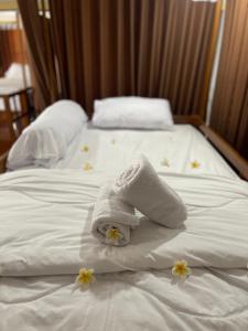 Kelingking Hostel في Klungkung: منشفة على سرير مع ورود عليه
