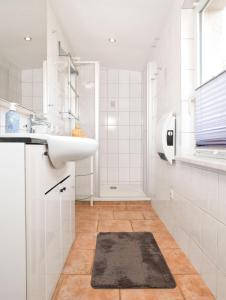 La salle de bains blanche est pourvue d'un lavabo et d'un miroir. dans l'établissement Meertied, à Oertzenhof