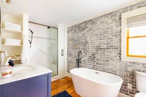 a bathroom with a white tub and a brick wall at Golden Acres Ranch Hot Tub+Gameroom+Creek & wifi in Highlands +85 photos