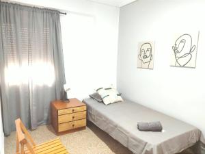 ein Schlafzimmer mit einem Bett, einer Kommode und einem Fenster in der Unterkunft Típico apartamento de pueblo in Faura