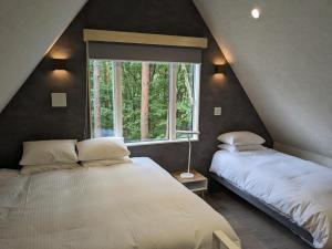 a attic bedroom with two beds and a window at Summit Chalets in Hakuba