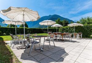 eine Gruppe von Tischen und Stühlen mit Sonnenschirmen in der Unterkunft B&B HOTEL Saint Jean De Maurienne in Sainte-Marie-de-Cuines