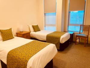 a hotel room with two beds and a chair and a window at Mary MacKillop Heritage Centre in Melbourne