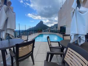 a patio with tables and chairs and a swimming pool at TOP LEBLON Flats in Rio de Janeiro