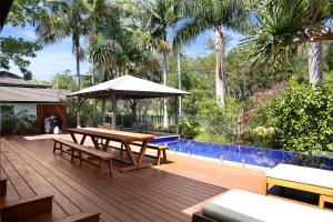 una terraza de madera con mesa de picnic y sombrilla en Away Guesthouse- Away on Shirley Lane, en Byron Bay