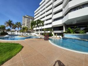 a swimming pool next to a large building at Executive Style Condo With Sea Views in Porlamar