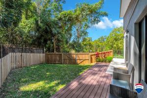 a backyard with a fence and a wooden walkway at Trinity Beach Escape in Trinity Beach