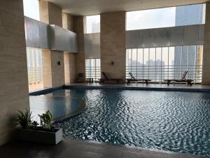 a large swimming pool in a building with windows at The H Tower Residence by YLS Stay in Jakarta