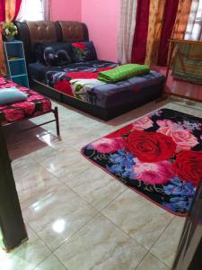 ein Wohnzimmer mit einem Sofa und einem Teppich mit Rosen in der Unterkunft ABAH HOMESTAY, MANIR, KUALA TERENGGANU, (HOMESTAY B) in Kuala Terengganu