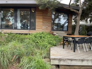 een houten terras met een tafel en stoelen voor een huis bij Tranquil Garden Studio with Stunning Lake Views in Ocean Grove