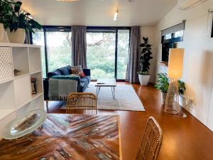 een woonkamer met een bank en een tafel bij Tranquil Garden Studio with Stunning Lake Views in Ocean Grove