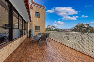 a patio with chairs and a table on a brick wall at Tuggeranong Short Stay #11C - Sleeps 8 in Canberra