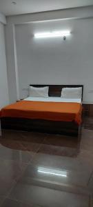 um quarto com uma cama com lençóis e almofadas laranja em Saritashray Seva Dham em Vrindavan