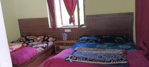 Zimmer mit 2 Betten und einem Fenster in der Unterkunft Badrinath House by Prithvi Yatra Hotel in Badrīnāth