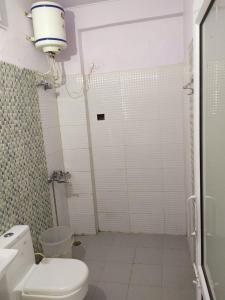 biała łazienka z toaletą i prysznicem w obiekcie Badrinath House by Prithvi Yatra Hotel w mieście Badrinath