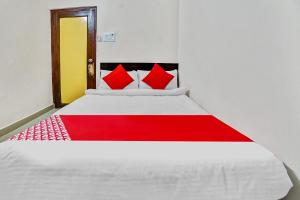 um quarto com uma cama branca e almofadas vermelhas em Collection O 45443 Hotel Suvidha em Bilāspur
