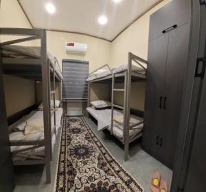 a room with three bunk beds and a rug at Al-Hilal Hostel in Samarkand