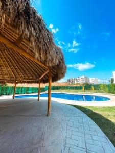 un ombrellone di paglia e una piscina di Departamento Ecoface Vallarta a Puerto Vallarta