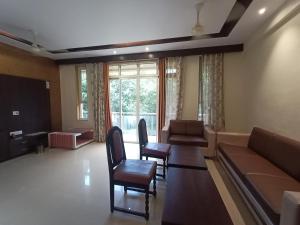 a living room with a couch and a table and chairs at Hotel Oakwood mahabaleshwar in Mahabaleshwar