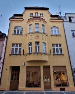 un edificio amarillo con balcones en una calle en Apartmány na Trojce, en Žatec