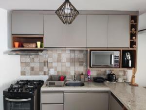 a kitchen with white cabinets and a sink and a stove at Casa de Veraneio na Praia do Francês in Marechal Deodoro