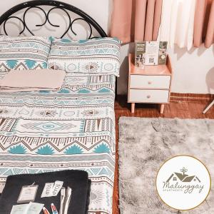um quarto com uma cama e uma mesa com uma mesa de cabeceira em Malunggay Apartments em Mariveles