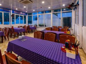 a restaurant with purple tables and chairs and windows at Cat Ba Hongkong Hotel in Cat Ba
