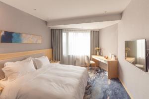 um quarto de hotel com uma cama branca e uma secretária em City Hotel Shanghai em Xangai