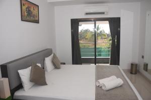 a bedroom with a large white bed with a window at Athi Resorts in Bogmalo