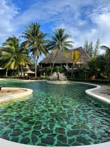 a swimming pool in front of a resort with palm trees at Beach front villa in Malindi in Malindi