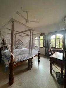sypialnia z łóżkiem z baldachimem i stołem w obiekcie Beach front villa in Malindi w mieście Malindi