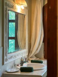 baño con lavabo, espejo y ventana en Beach front villa in Malindi en Malindi