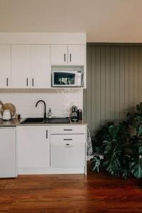 a white kitchen with a sink and a microwave at Meander Valley Vineyard Escape in Red Hill