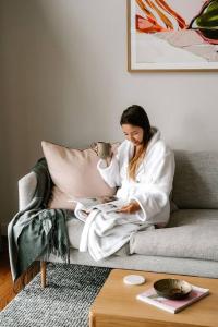 a woman sitting on a couch reading a magazine at Meander Valley Vineyard Escape in Red Hill