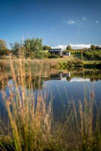 a reflection of a house in the water of a lake at Meander Valley Vineyard Escape in Red Hill