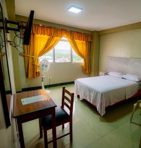 a bedroom with a bed and a desk and a window at Hotel Zulema Inn in Esmeraldas